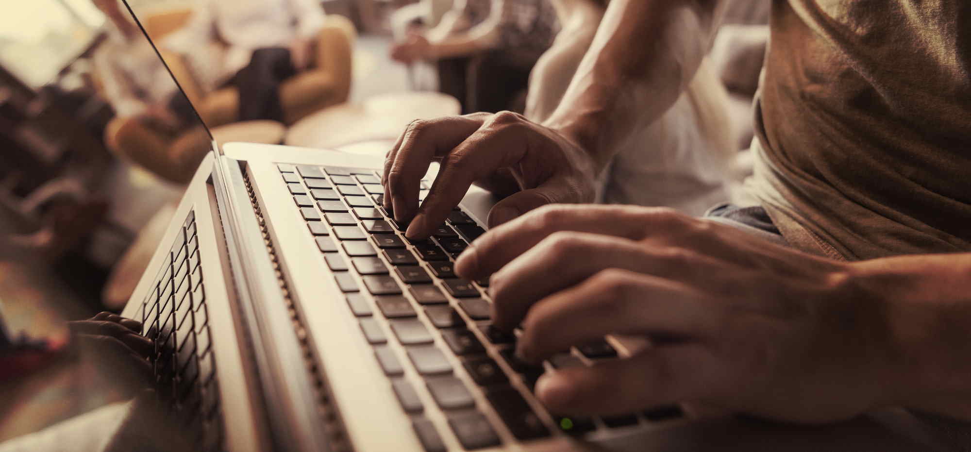 close up of male hands while typing on laptop computer in modern office